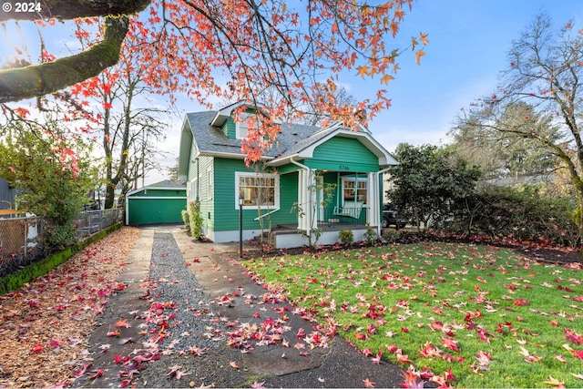 view of front of property with a porch, a front lawn, an outdoor structure, and a garage