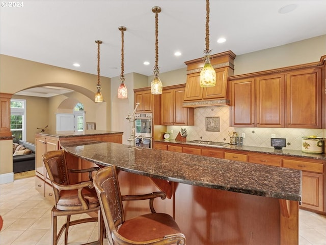 kitchen with stainless steel appliances, hanging light fixtures, a breakfast bar, and a kitchen island with sink