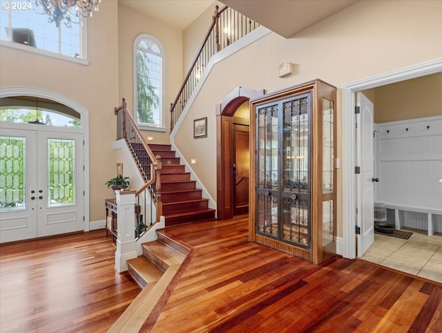 foyer with french doors, a notable chandelier, wood-type flooring, and a high ceiling