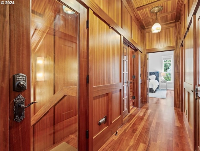 hallway with a towering ceiling, wooden walls, wooden ceiling, and wood-type flooring