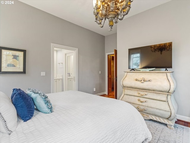 bedroom with ensuite bathroom, wood-type flooring, and an inviting chandelier