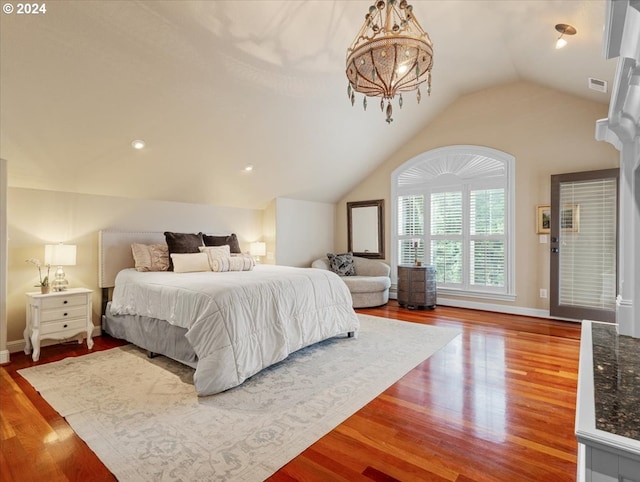 bedroom with an inviting chandelier, hardwood / wood-style flooring, and vaulted ceiling