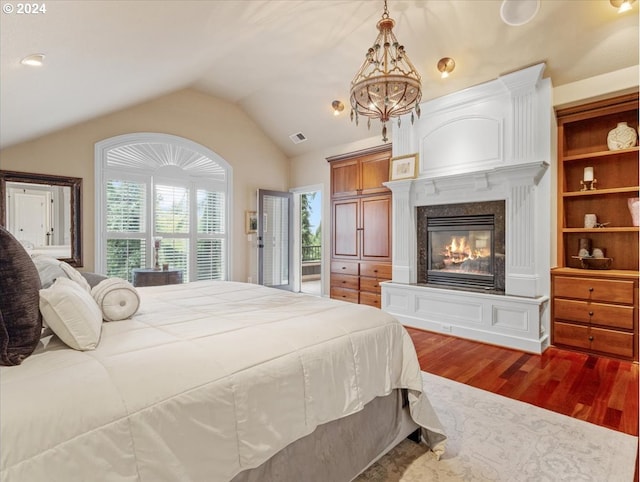 bedroom with a premium fireplace, lofted ceiling, and hardwood / wood-style floors