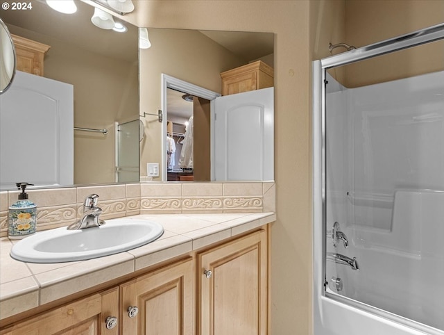 bathroom with vanity, tasteful backsplash, and bath / shower combo with glass door