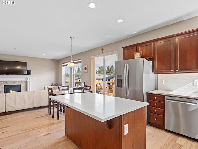 kitchen with a center island, stainless steel appliances, pendant lighting, light hardwood / wood-style floors, and decorative backsplash