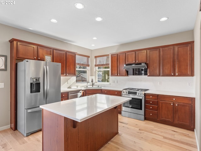 kitchen with a kitchen breakfast bar, sink, light hardwood / wood-style flooring, appliances with stainless steel finishes, and a kitchen island