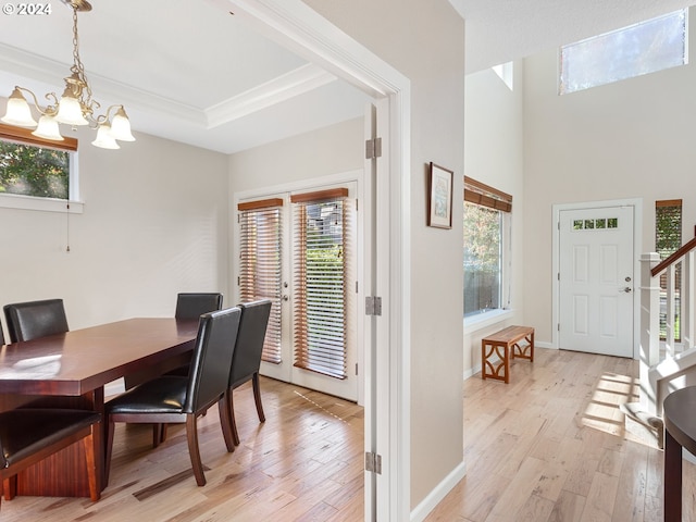 dining room featuring a tray ceiling, light hardwood / wood-style flooring, a chandelier, and ornamental molding