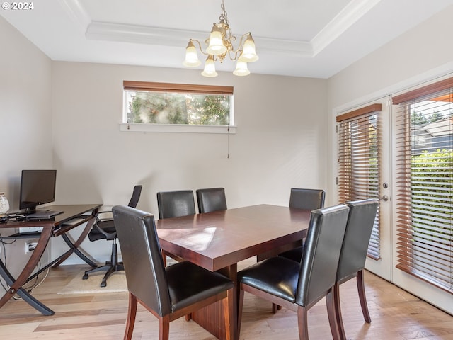 dining area with a raised ceiling, ornamental molding, light hardwood / wood-style flooring, and an inviting chandelier