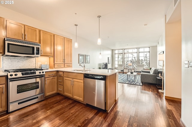 kitchen with dark wood-type flooring, sink, decorative light fixtures, appliances with stainless steel finishes, and kitchen peninsula