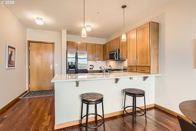 kitchen featuring a kitchen bar, sink, decorative light fixtures, appliances with stainless steel finishes, and kitchen peninsula