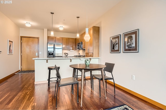 kitchen featuring hanging light fixtures, a kitchen breakfast bar, stainless steel appliances, dark hardwood / wood-style flooring, and kitchen peninsula