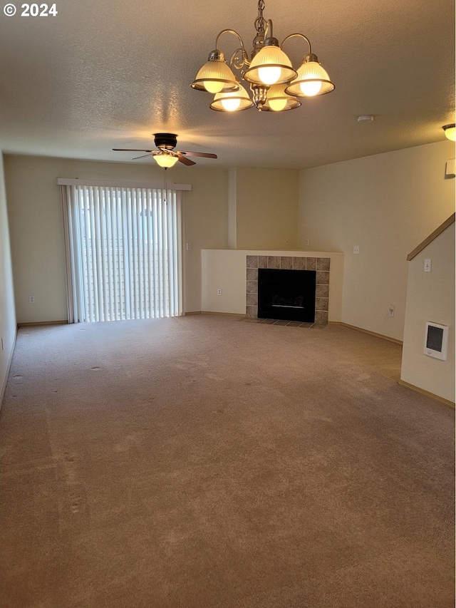 unfurnished living room with carpet, a textured ceiling, a tiled fireplace, and ceiling fan with notable chandelier