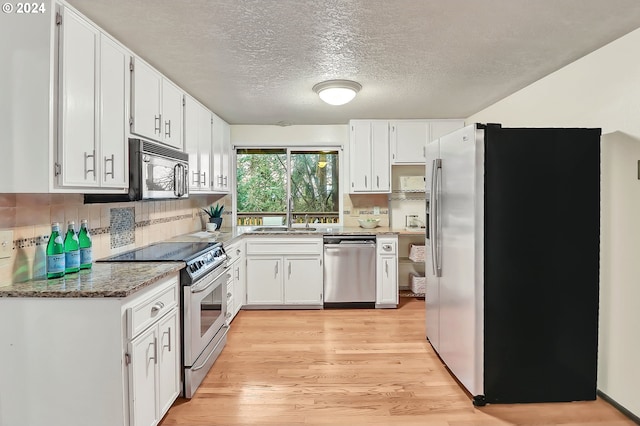 kitchen featuring sink, stainless steel appliances, light stone counters, light hardwood / wood-style flooring, and white cabinets