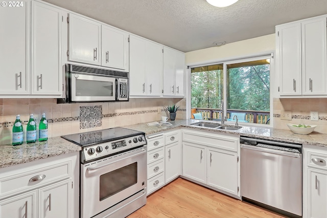 kitchen featuring white cabinets, appliances with stainless steel finishes, light hardwood / wood-style floors, and sink