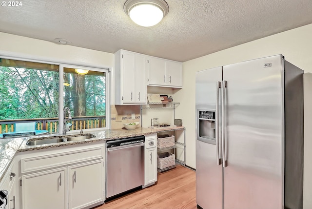 kitchen with sink, white cabinets, stainless steel appliances, and light hardwood / wood-style flooring