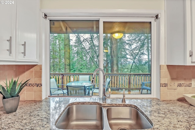 kitchen with white cabinetry, light stone counters, tasteful backsplash, and sink