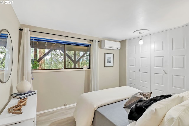 bedroom with a wall mounted air conditioner, light hardwood / wood-style flooring, and a closet