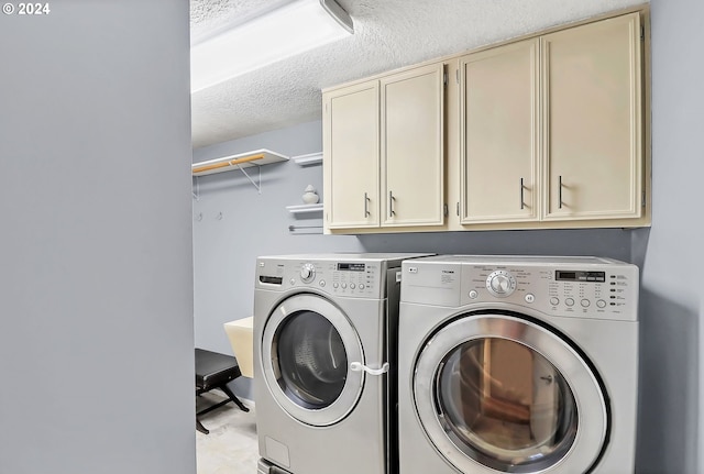 washroom featuring cabinets, washing machine and dryer, and a textured ceiling