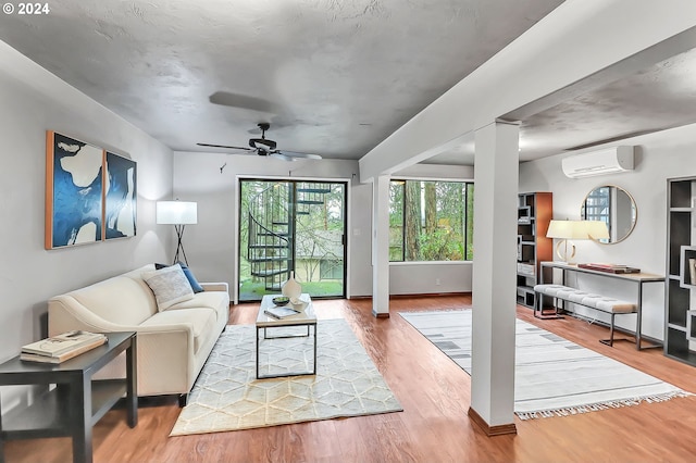 living room with a wall mounted air conditioner, ceiling fan, and hardwood / wood-style flooring