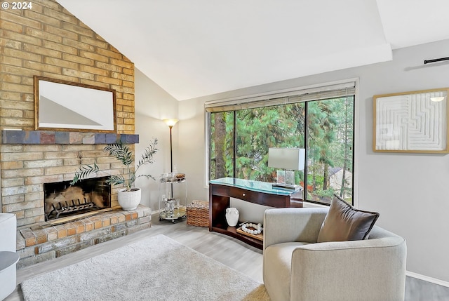 living room featuring hardwood / wood-style flooring, vaulted ceiling, and a brick fireplace