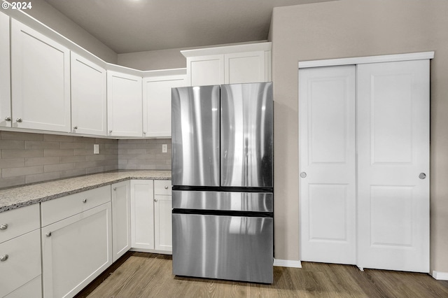 kitchen featuring white cabinets, stainless steel fridge, light stone counters, and light hardwood / wood-style flooring