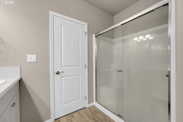 bathroom with wood-type flooring, vanity, and a shower with door