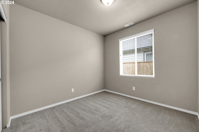 carpeted empty room with a textured ceiling