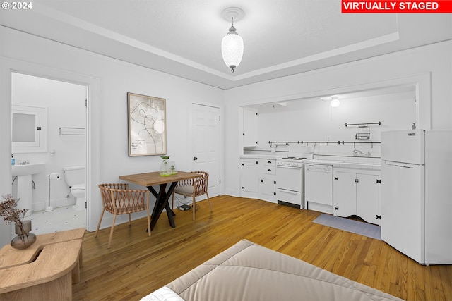 dining room featuring light wood-type flooring, baseboards, and a raised ceiling