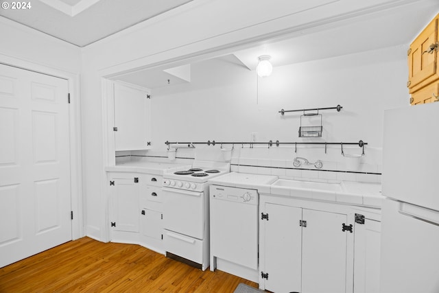 kitchen featuring white appliances, light wood-type flooring, a sink, and white cabinetry