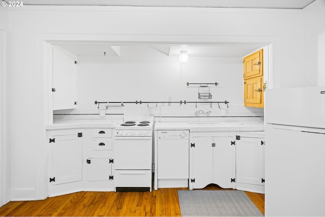 kitchen with white appliances, a sink, white cabinetry, light countertops, and light wood finished floors