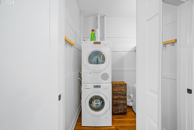 clothes washing area featuring laundry area, stacked washer / dryer, and wood finished floors