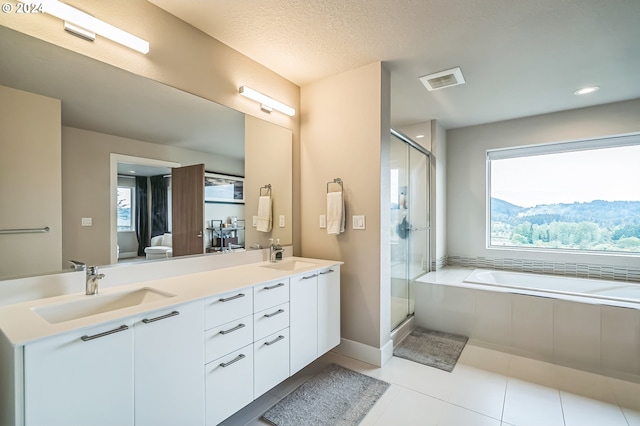 bathroom featuring tile patterned floors, vanity, separate shower and tub, and a textured ceiling