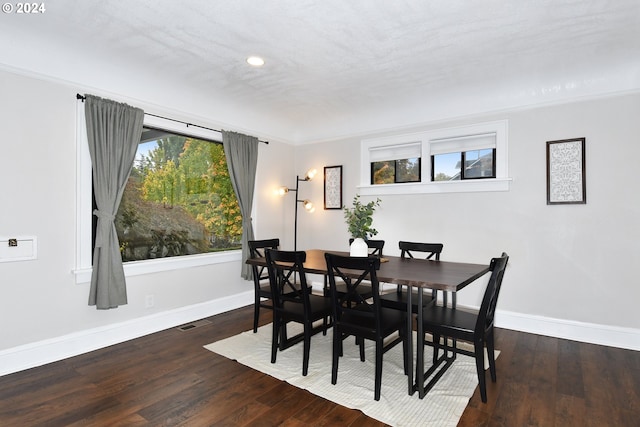 dining space with dark hardwood / wood-style flooring, crown molding, and a wealth of natural light