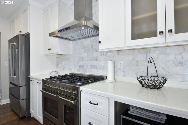 kitchen featuring high end appliances, backsplash, white cabinets, wall chimney range hood, and dark hardwood / wood-style floors