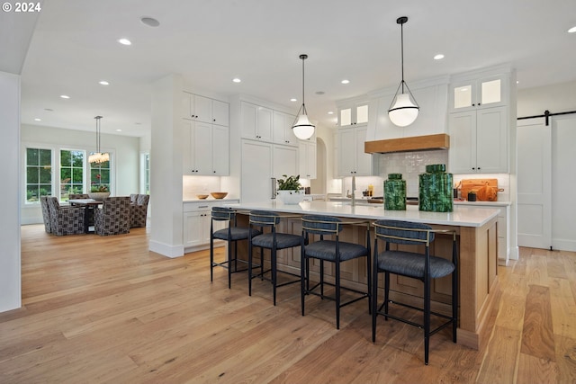 kitchen featuring hanging light fixtures, white cabinetry, a barn door, and a large island