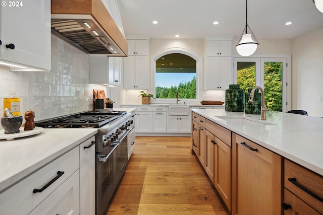 kitchen featuring pendant lighting, sink, white cabinetry, custom range hood, and range with two ovens