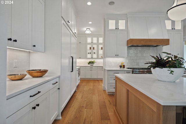 kitchen featuring custom exhaust hood, white cabinetry, and hanging light fixtures