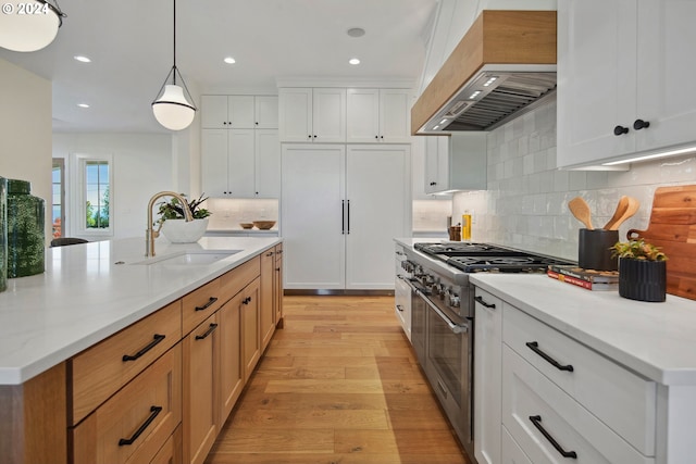 kitchen with white cabinetry, premium appliances, and a center island with sink