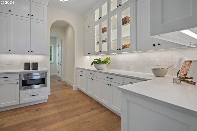 kitchen featuring backsplash, white cabinets, and light wood-type flooring