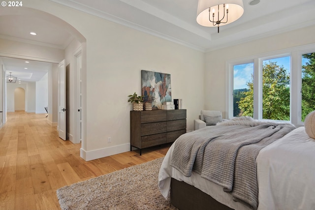 bedroom featuring crown molding, a tray ceiling, and light hardwood / wood-style flooring