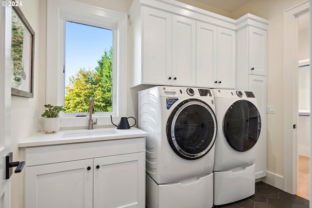 clothes washing area with cabinets, washing machine and dryer, sink, and dark tile patterned flooring