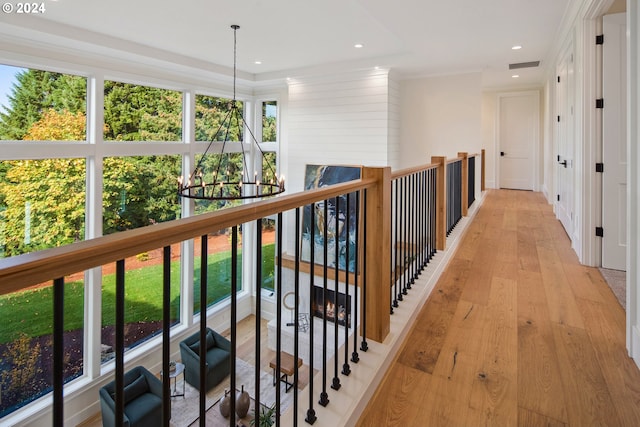 hallway with a wealth of natural light, a notable chandelier, and light hardwood / wood-style flooring