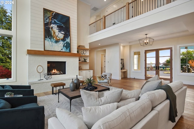 living room featuring a fireplace, light hardwood / wood-style flooring, and french doors