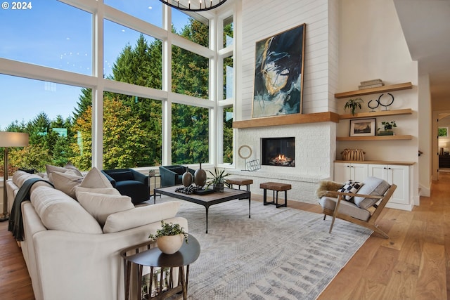 living room featuring a large fireplace, a chandelier, light hardwood / wood-style floors, and a high ceiling