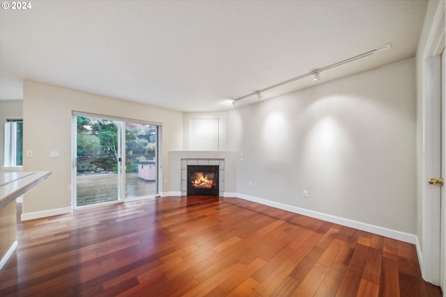 unfurnished living room with a fireplace, wood-type flooring, and rail lighting