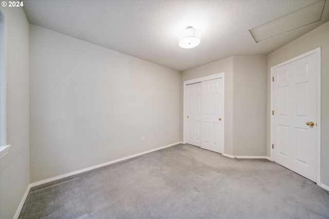 unfurnished bedroom featuring a textured ceiling, light carpet, and a closet