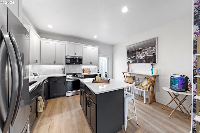 kitchen featuring appliances with stainless steel finishes, tasteful backsplash, white cabinets, a center island, and light wood-type flooring