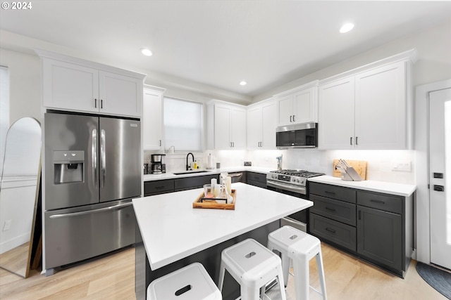 kitchen with light hardwood / wood-style flooring, decorative backsplash, stainless steel appliances, and white cabinetry