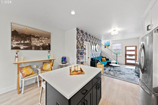 kitchen with stainless steel fridge, a kitchen bar, light wood-type flooring, and a kitchen island