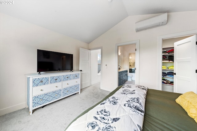 bedroom featuring an AC wall unit, lofted ceiling, light colored carpet, and ensuite bathroom